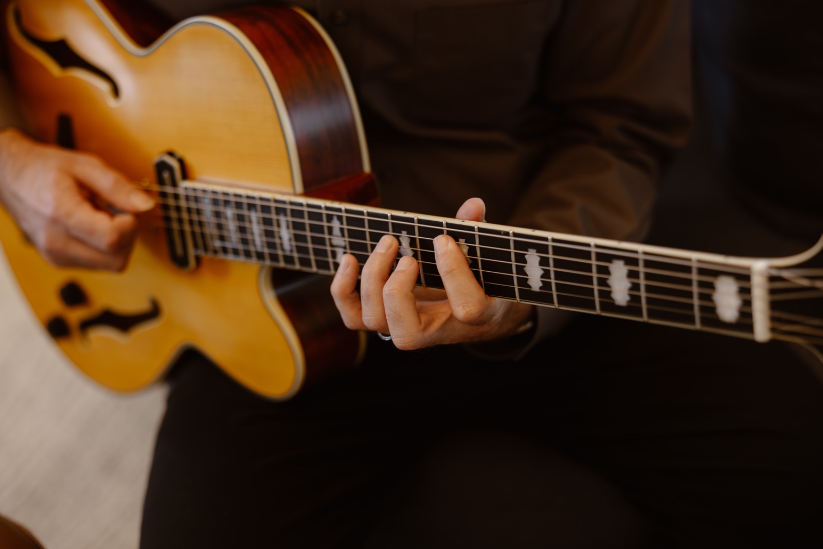Marc's hands on the fretboard of an archtop guitar