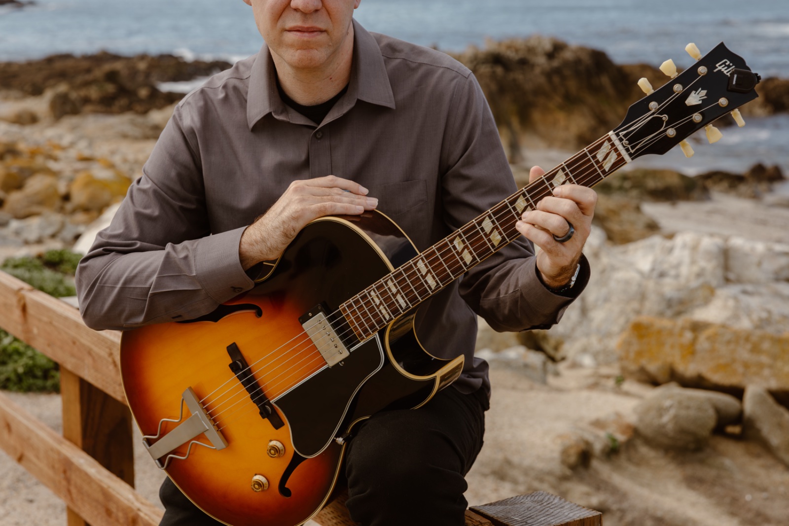 Marc with an archtop guitar by the ocean